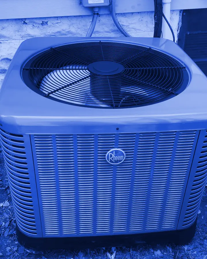 Air conditioner condenser installed outside a home, shown in a blue duotone