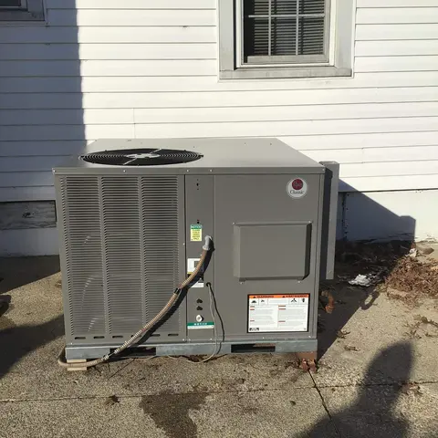 Packaged rooftop-style HVAC unit installed beside a house